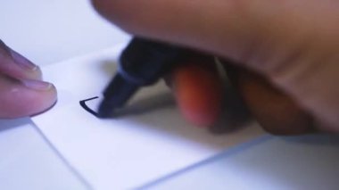 Beyaz kağıda yazan kişinin yakın plan görüntüsü - Sahte Haber