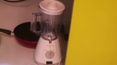 Ethnic Woman Getting Blender From A Cupboard