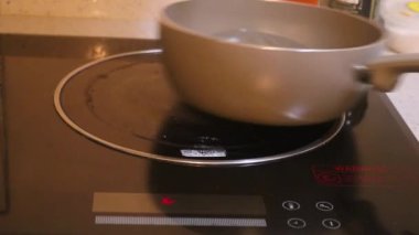 Ethnic Woman Placing Pot On Electric Stove