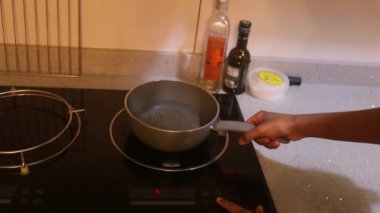 Ethnic Woman Placing Pot On Electric Stove