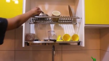 Ethnic Woman Taking Dry Dishes Off Of Rack