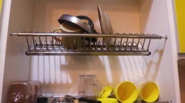 Ethnic Woman Taking Dry Dishes Off Of Rack