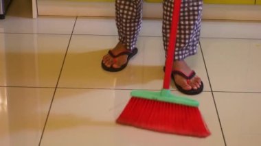 Pijamalı Müslüman kadın mutfağı süpürüyor.