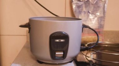 Rice Cooker Being Switched On By Ethnic Woman 