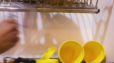 Ethnic Woman Taking Dry Dishes Off Of Rack
