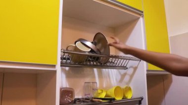 Ethnic Woman Taking Dry Dishes Off Of Rack
