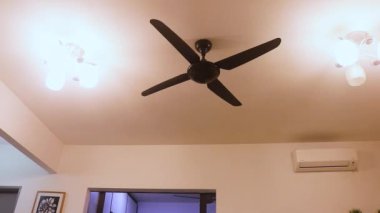 Oturma odasındaki elektrikli vantilatör düşük hızda çalışıyor.