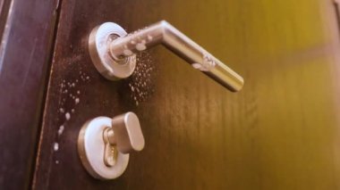 Kapı kolu eldivenli bir kadın tarafından dezenfekte ediliyor. 