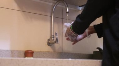 Eldivenli kadın evde bulaşık yıkıyor.