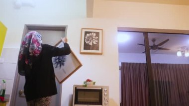 Bir kadın tarafından duvara yerleştirilen resim.