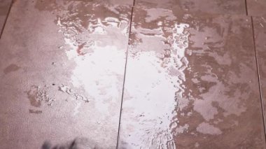 Banyo zemininde su var. Kadın tarafından paspaslanıyor.