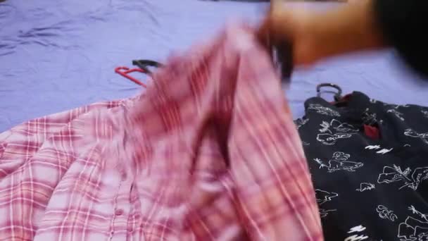 ハンガーにパターン化された服を置くエスニックな女性 Closeup — ストック動画