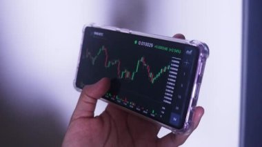 Woman Holding Phone In Landscape Mode Checking Binance's Hourly Chart