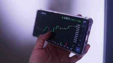 Woman Holding Phone In Landscape Mode Checking Ethereum's Hourly Chart