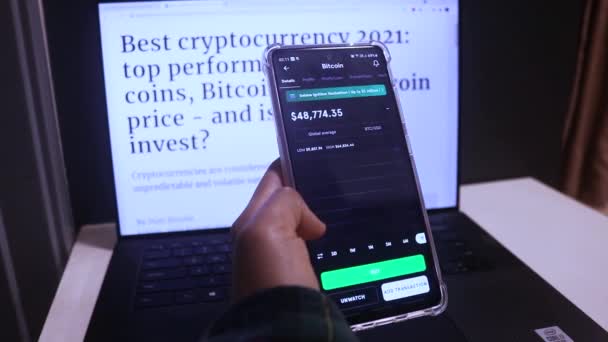 Vrouw Onderzoeken Bitcoin Jaarlijkse Voorraden Telefoon Met Laptop — Stockvideo