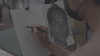Asyalı bir adam kalem çizimi yapıyor.