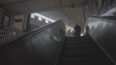 Malezyalı bir adam tren istasyonunda yürüyen merdivenden çıkıyor.