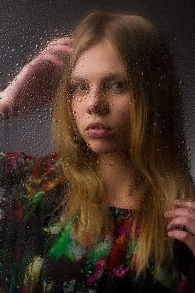 Portret van een mooi meisje achter NAT glas op een zwarte achtergrond. — Stockfoto