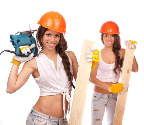 Gemini girls in orange helmets with an electric drill and electric saw on a white background. — Stock Photo, Image
