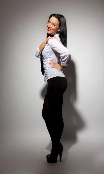 Güzel kız beyaz bir gömlek ve gri bir arka plana sahip siyah bir etek — Stok fotoğraf