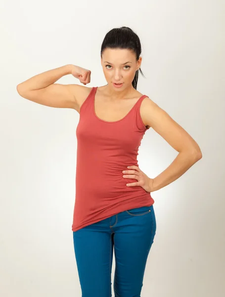 Beautiful girl in a red shirt and blue jeans on a gray background — Stock Photo, Image
