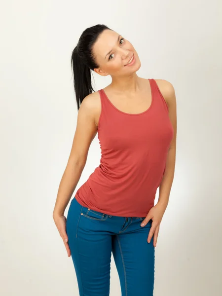 Hermosa chica en una camisa roja y vaqueros azules sobre un fondo gris —  Fotos de Stock