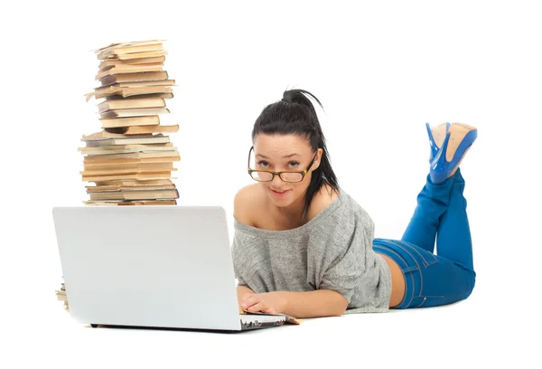 Beautiful female student lying on the floor with laptop and books on a white background — Stock Photo, Image