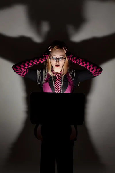 Girl looking in the laptop sitting on a gray background. — Stock Photo, Image