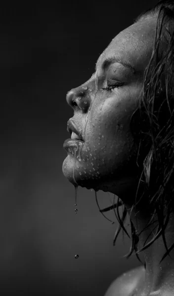 A lány arcát, milyen víz folyik a sötét háttéren portréja — Stock Fotó