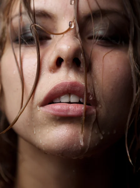 Porträt eines Mädchengesichts, dessen Wasser auf einem dunklen Hintergrund fließt — Stockfoto