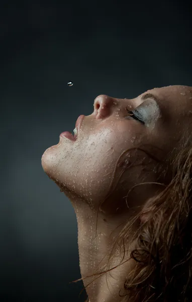 Retrato de la cara de una chica cuyo agua fluye sobre un fondo oscuro . Imagen de stock