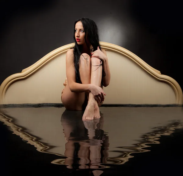 Girl with wet hair and wet clothes sitting in the black water on a black background — Stock Photo, Image