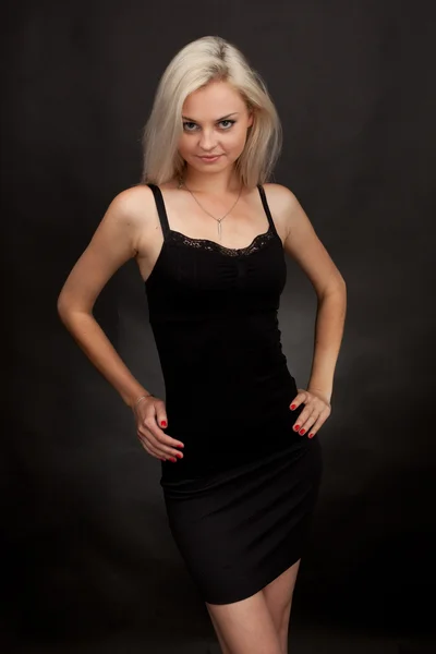 Beautiful girl in a short black dress on a black background — Stock Photo, Image