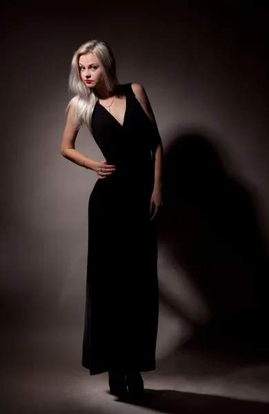Schönes Mädchen in einem langen schwarzen Kleid auf grauem Hintergrund — Stockfoto