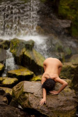genç kız ıslak ıslak taşlar üzerinde şelale, güzel bir vücut.