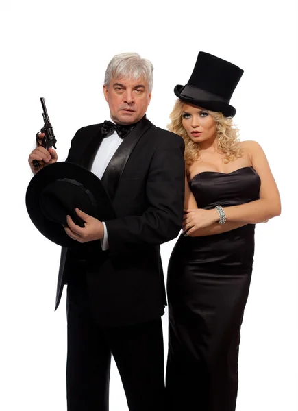 Homem e mulher em ternos e chapéus elegantes com um revólver — Fotografia de Stock