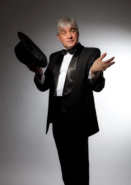 Elegante hombre en esmoquin y sombrero sobre fondo gris — Foto de Stock