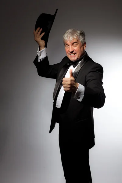 Elegant man in tuxedo and hat on a gray background