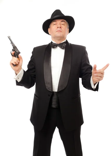 De elegante man in een smoking met een hoed en een revolver op een witte achtergrond — Stockfoto