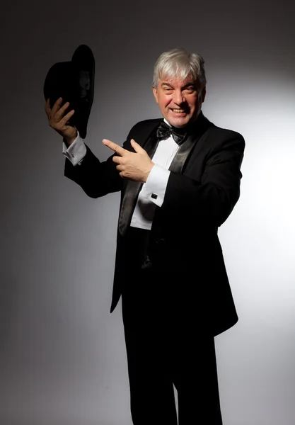 Elegante hombre en esmoquin y sombrero sobre fondo gris — Foto de Stock