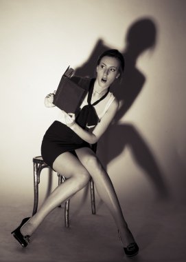 Kız bir sandalyede oturuyor ve korkunç bir kitap okuma