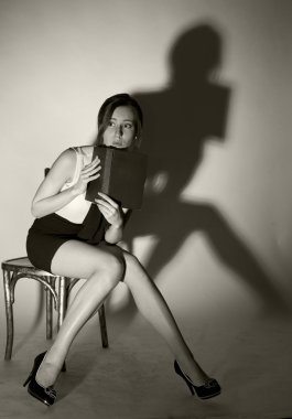 Kız bir sandalyede oturuyor ve korkunç bir kitap okuma