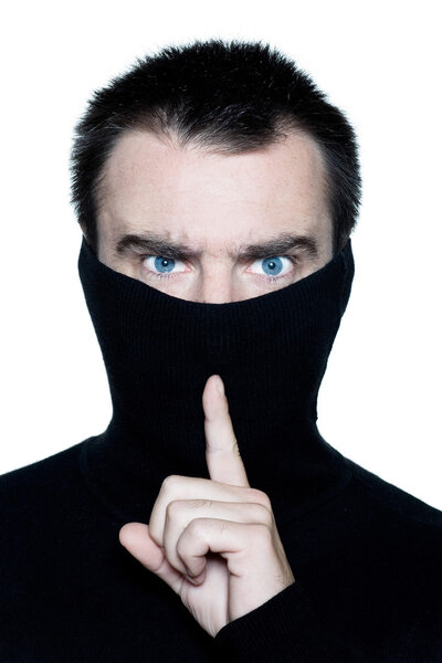 man hiding behind his turtle polo neck gesturing silence