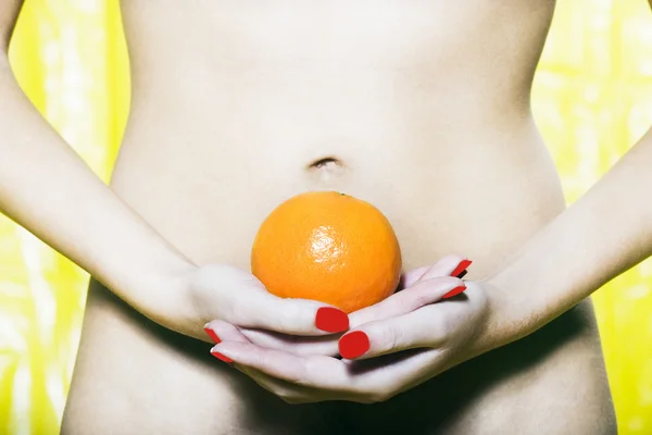 女人腹部持有橙 图库图片