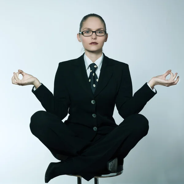 Studio shot portrait of a beautiful young woman in a costume suit sitting on the lotus posture — Stock Photo, Image