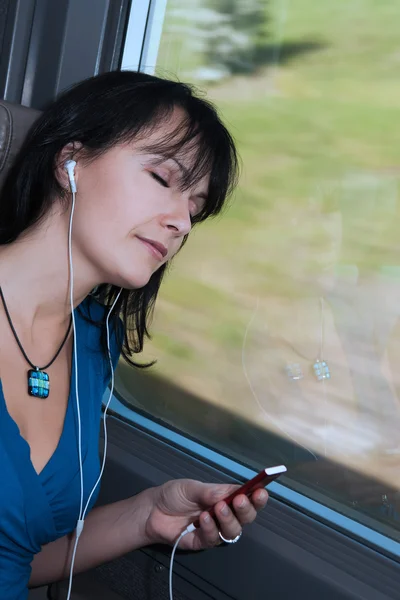 Bella giovane donna sognando in un treno ascoltando musica su un tipo di iPod lettore mp3 — Foto Stock