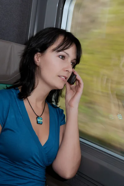 火车上漂亮的年轻女子笑着打了一个电话 — 图库照片