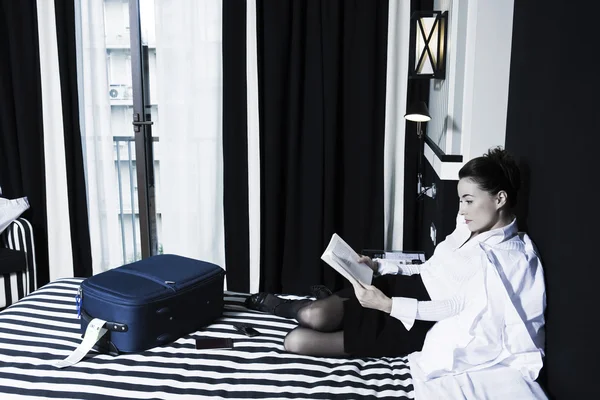 Woman reading a book in a hotel bedroom — Stock Photo, Image