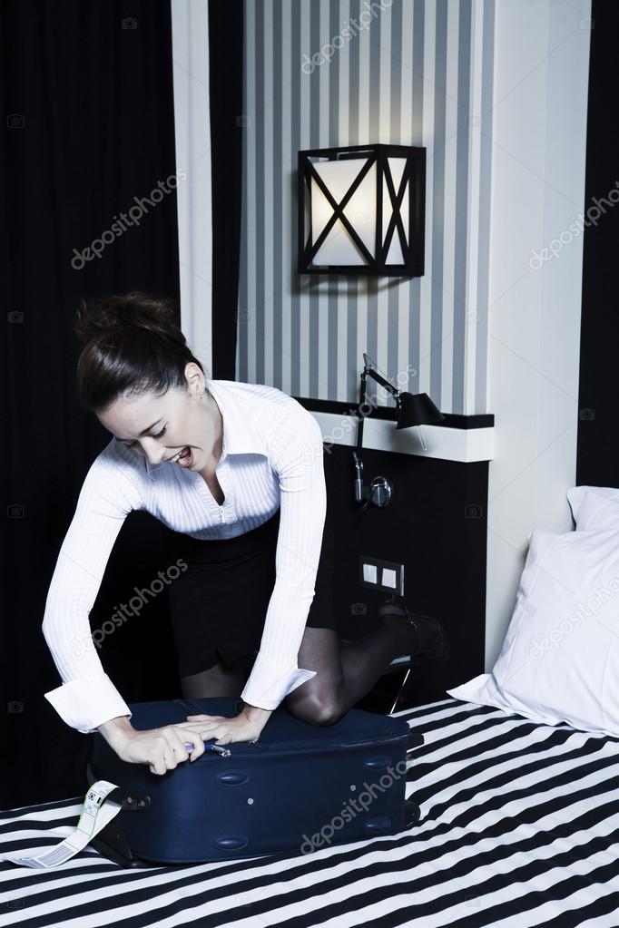 Woman packing difficulty in a hotel bedroom