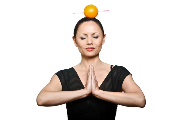 Portrait of beautiful woman with orange on head and hands joined Stock Image